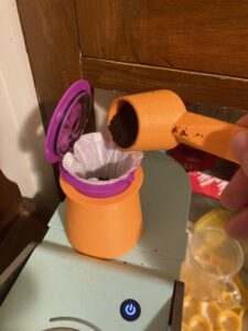 Coffee pod in stand, with scoop pouring coffee grounds in